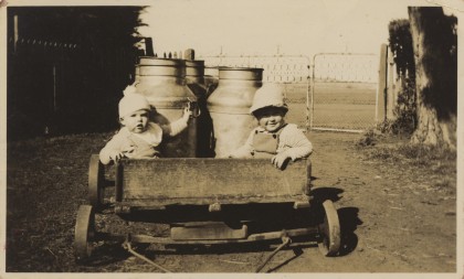 Two babies in a wooden milk cart