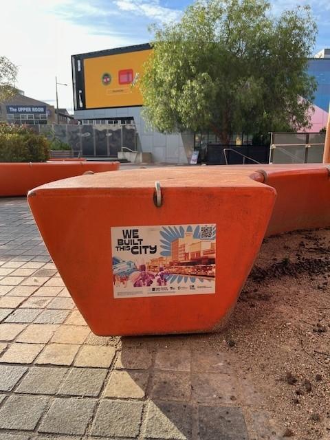 a sticker for We Built This City on an orange bollard outside 